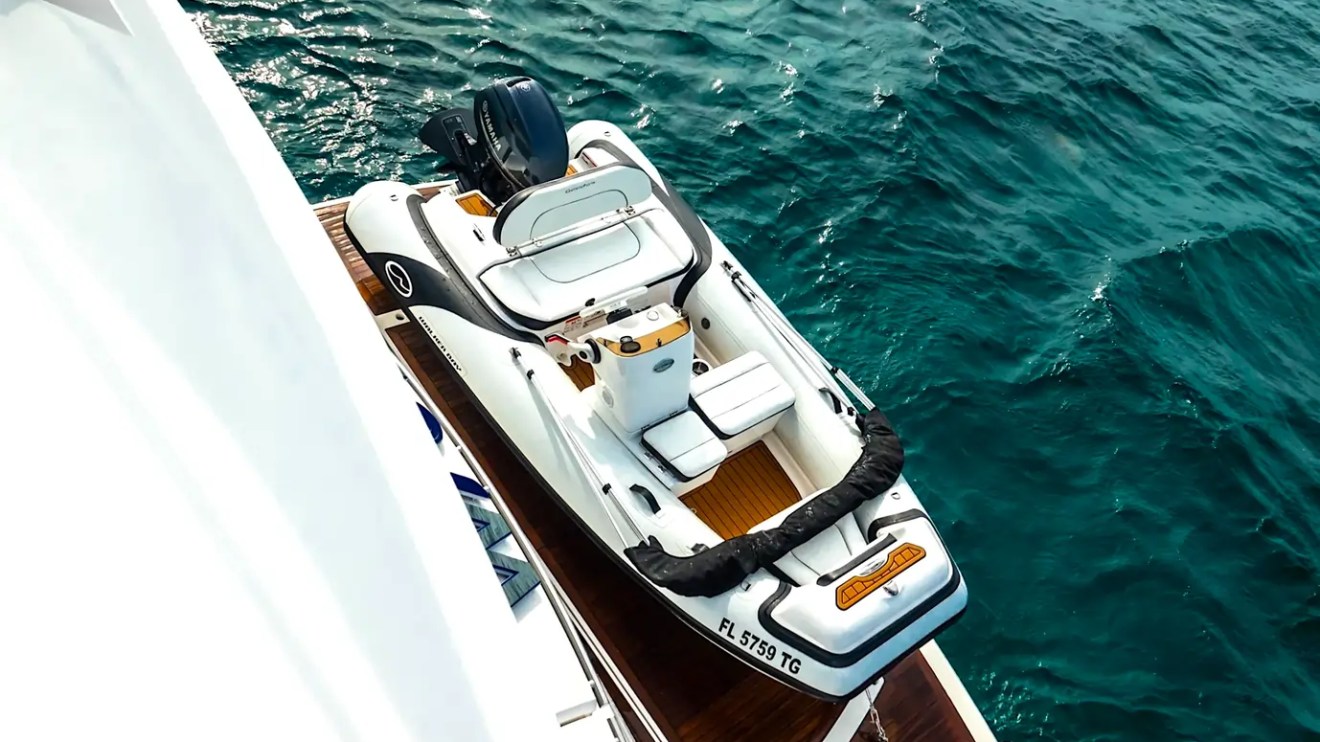 75' Sunseeker Yacht Charter tender secured alongside the yacht, featuring teak accents, helm seating, and clear turquoise waters near Nassau in The Bahamas.