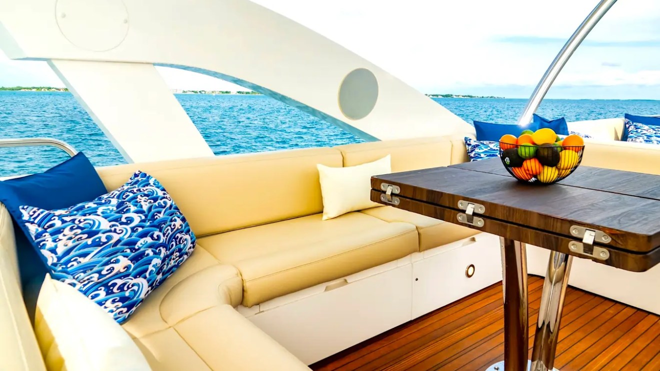 75' Sunseeker Yacht Charter aft lounge featuring wraparound cushioned seating, teak decking, dining table, and open-water views near Paradise Island in The Bahamas.