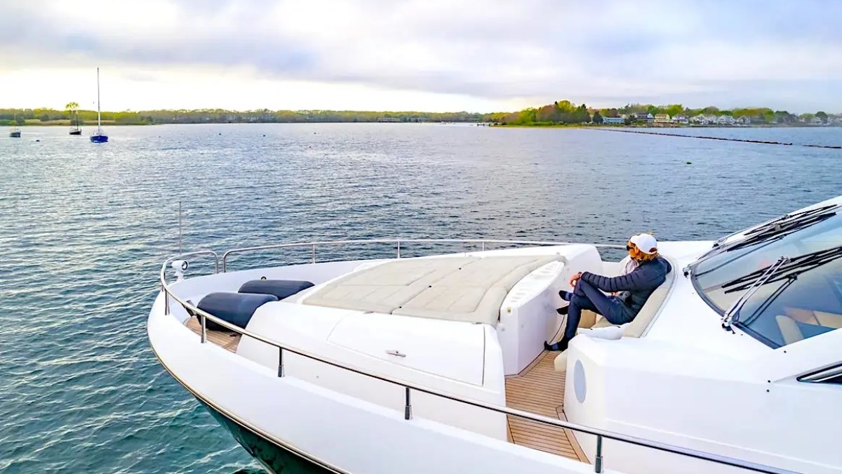 75' Sunseeker Yacht Charter bow lounge featuring a guest relaxing beside the foredeck sun pad with open-water views near Paradise Island in The Bahamas.