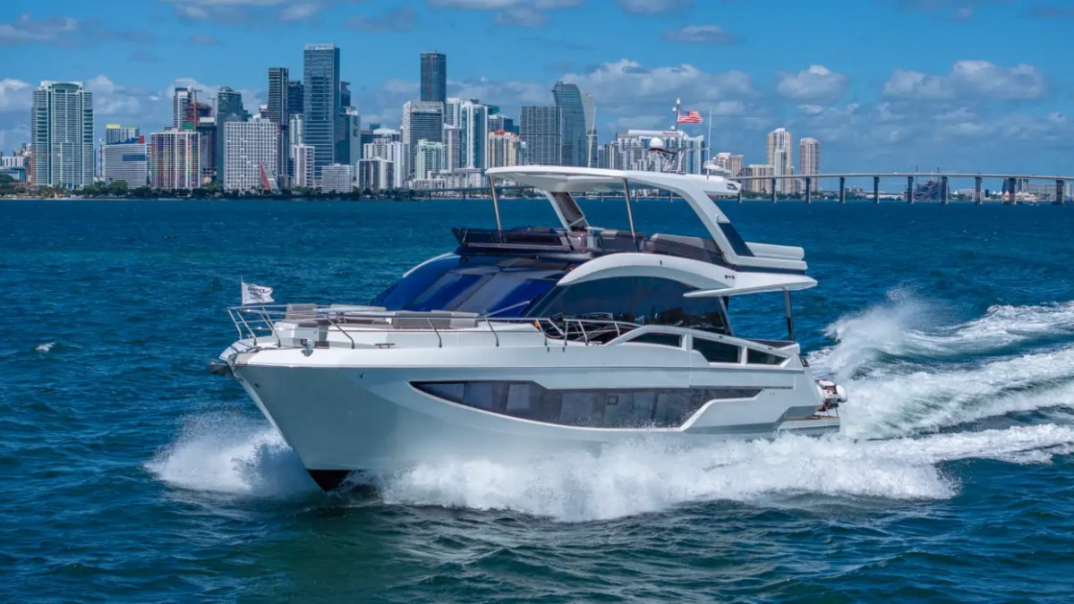 68' Galeon Yacht Charter cruising across Biscayne Bay with the Downtown Miami skyline in the background showcasing the sleek profile and flybridge near Key Biscayne.