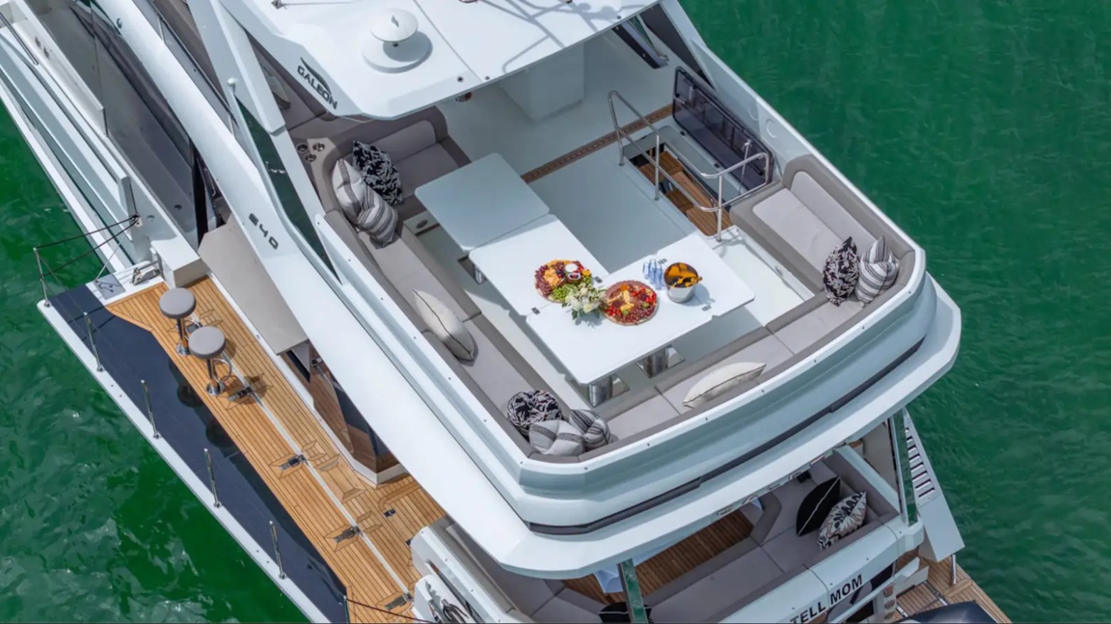 68' Galeon Yacht Charter flybridge lounge with spacious aft seating dining table and teak side decks during an aerial view in Key Biscayne on Biscayne Bay.