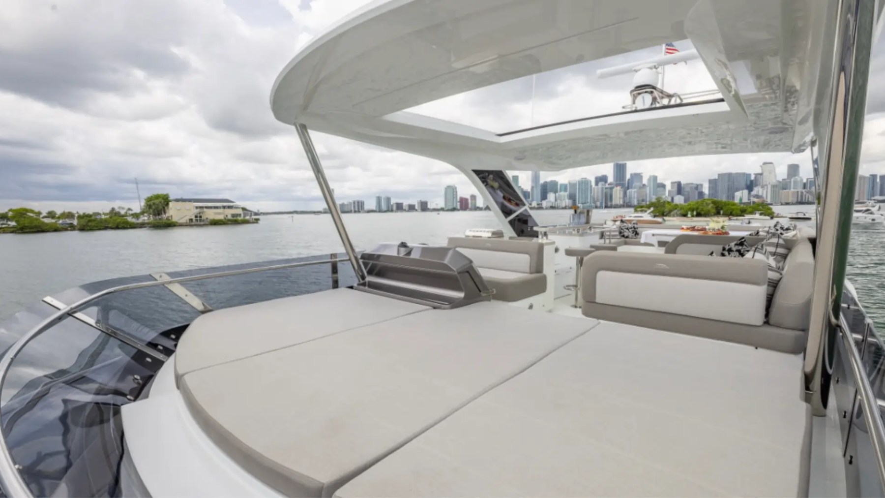 68' Galeon Yacht Charter featuring the spacious foredeck sun pad with panoramic Downtown Miami skyline views while anchored near Key Biscayne on Biscayne Bay.