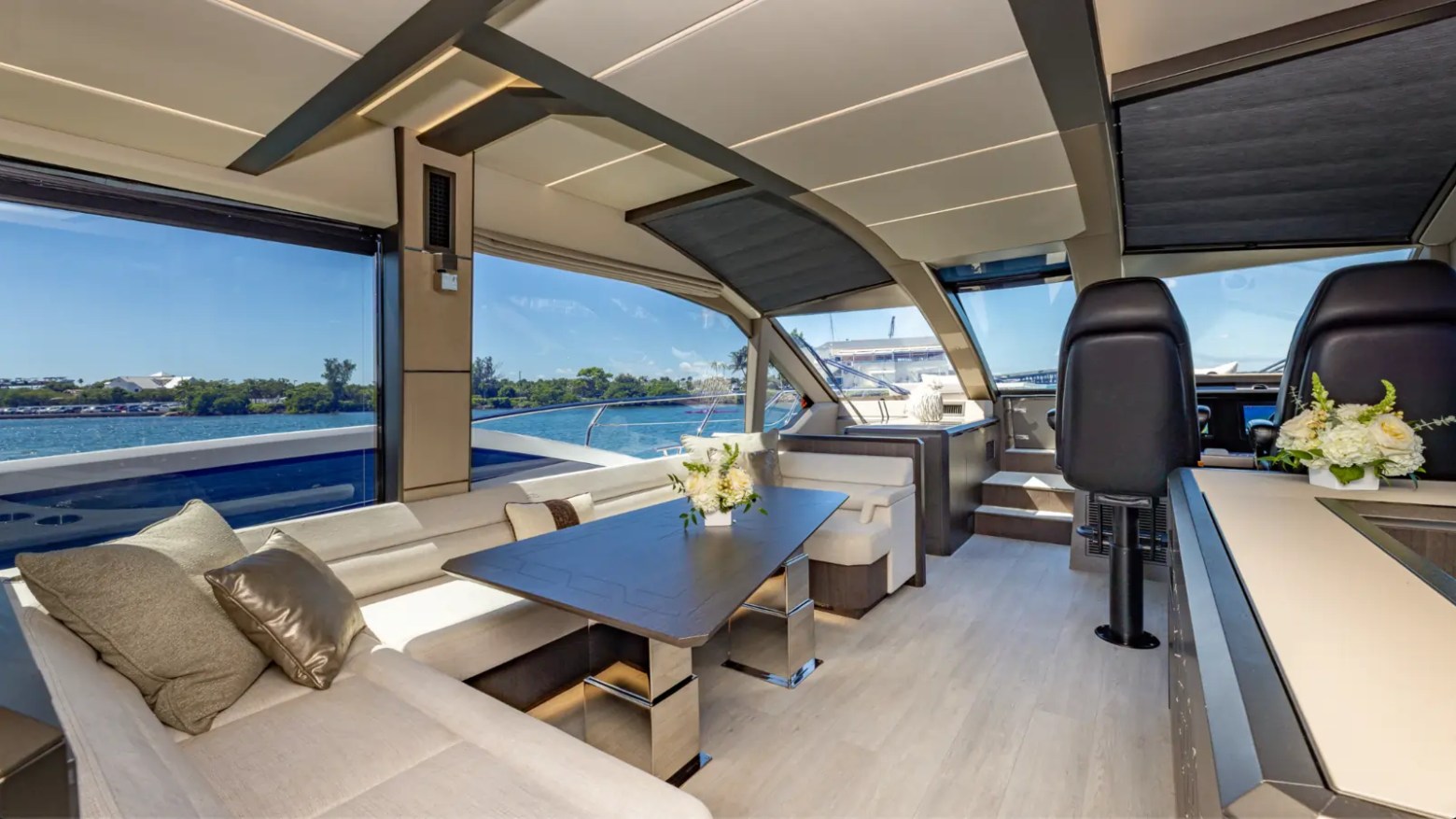 68' Galeon Yacht Charter displaying the contemporary salon with wraparound seating panoramic windows dining table and helm station while cruising near Key Biscayne on Biscayne Bay.