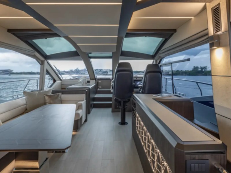 68' Galeon Yacht Charter featuring the modern salon with panoramic windows elegant dining area helm station and open interior views while cruising near Key Biscayne on Biscayne Bay.