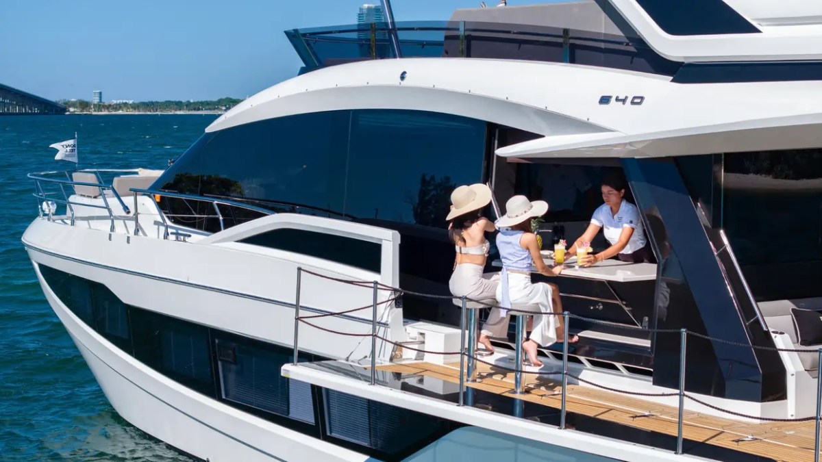 68' Galeon Yacht Charter showcasing the signature side terrace with the retractable galley serving bar and waterside seating while anchored near Key Biscayne on Biscayne Bay.