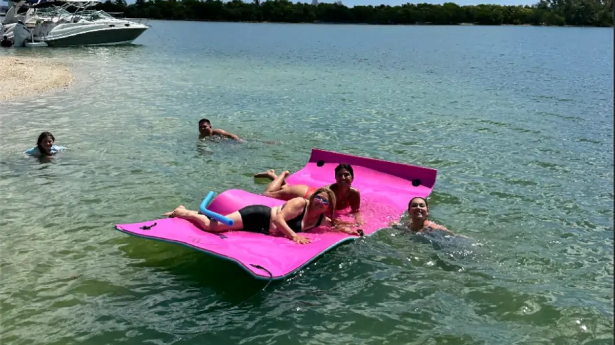 Guests enjoying the Magic Carpet floating mat during a 30' Hurricane Boat Rental in Miami.