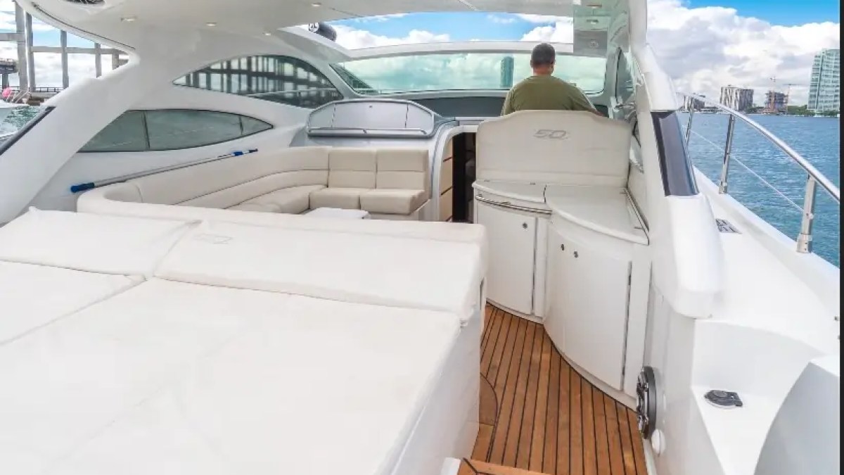 50' Pershing Yacht Charter aft sun pad leading to the cockpit lounge with helm seating, teak decking, and open-air cruising space on Biscayne Bay in Miami.