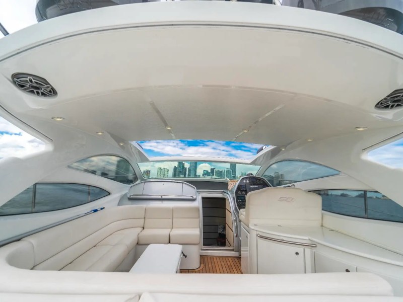 50' Pershing Yacht Charter cockpit featuring wraparound lounge seating, helm station, teak decking, and panoramic views of the Miami skyline while cruising on Biscayne Bay.
