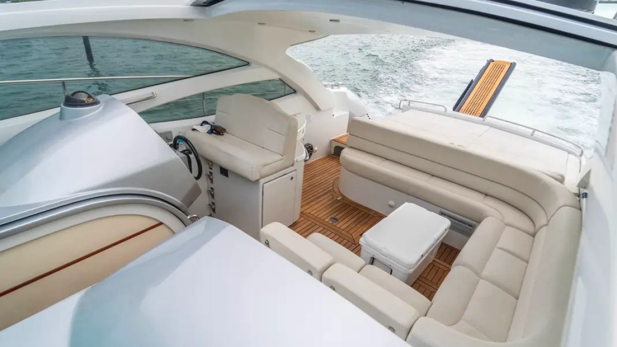 50' Pershing Yacht Charter cockpit featuring wraparound lounge seating, teak decking, helm controls, and an aft sun pad while cruising across Biscayne Bay in Miami.