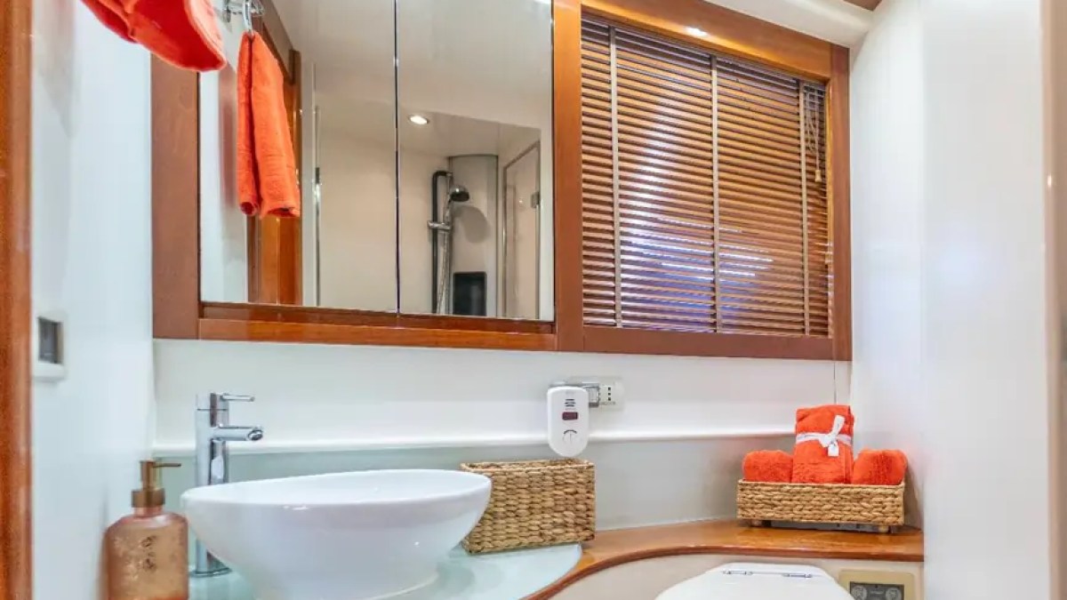 50' Pershing Yacht Charter ensuite bathroom featuring a modern vessel sink, vanity, wood cabinetry, shower access, and premium finishes aboard this Miami luxury yacht.