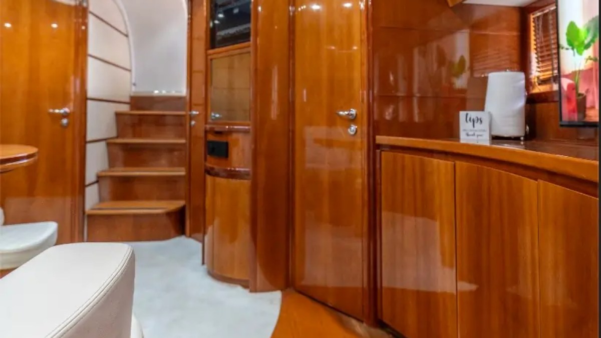 50' Pershing Yacht Charter interior featuring polished wood cabinetry, companionway stairs, premium storage, and refined salon finishes aboard this Miami luxury yacht.