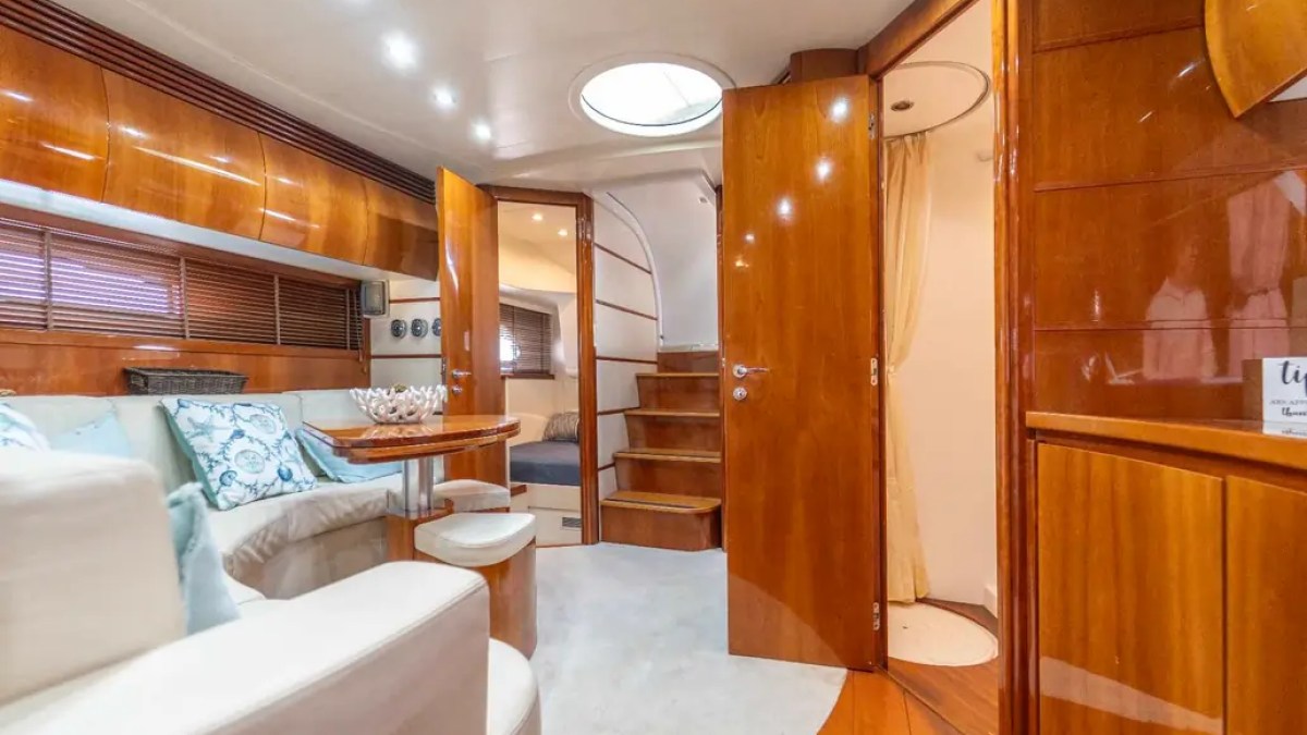 50' Pershing Yacht Charter interior lounge featuring polished wood cabinetry, wraparound seating, a dining table, and companionway access while cruising in Miami.