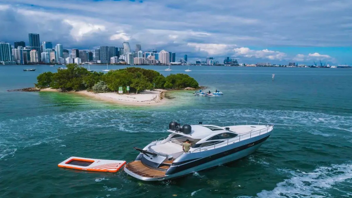 50' Pershing Yacht Charter captured from a waterfront aerial featuring the inflatable ocean pool and Downtown Miami skyline while anchored near Key Biscayne on Biscayne Bay.