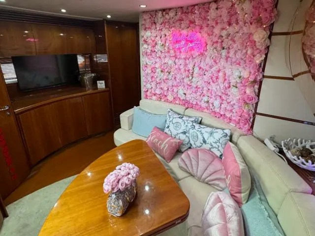 50' Pershing Yacht Charter luxury salon decorated with an elegant pink floral feature wall plush lounge seating and entertainment area while cruising in Miami on Biscayne Bay.