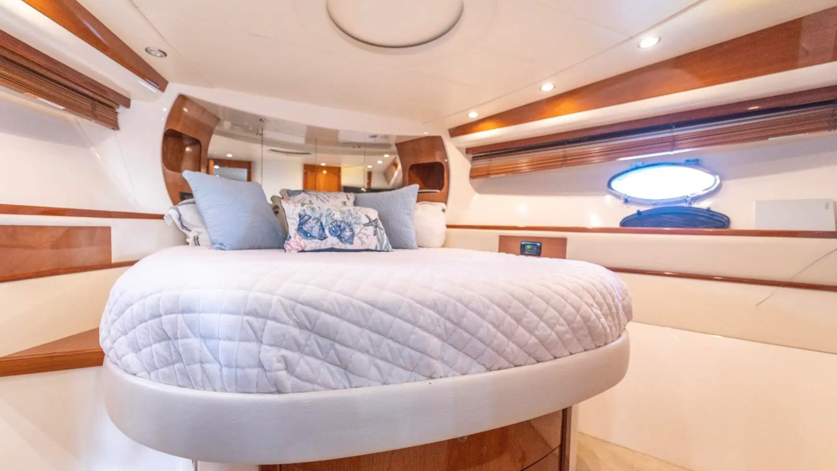 50' Pershing Yacht Charter master stateroom featuring a queen berth, panoramic hull windows, premium wood accents, and elegant cabin accommodations in Miami.