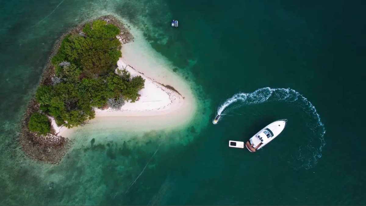 50' Pershing Yacht Charter captured from a top-down drone view anchored beside a secluded island with an inflatable ocean pool in Biscayne Bay near Key Biscayne.