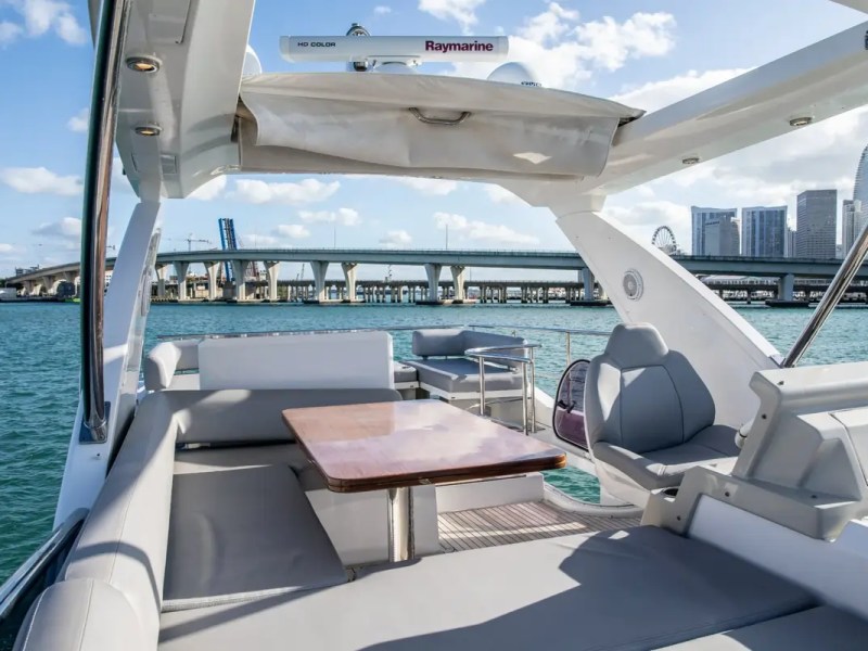 Aft cockpit aboard a 52' Azimut Yacht Charter featuring outdoor dining, helm seating and Miami waterfront views.