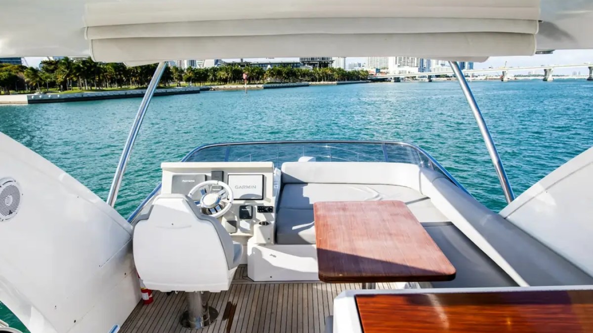 Flybridge aboard a 52' Azimut Yacht Charter featuring upper helm, dining table and panoramic Miami water views.