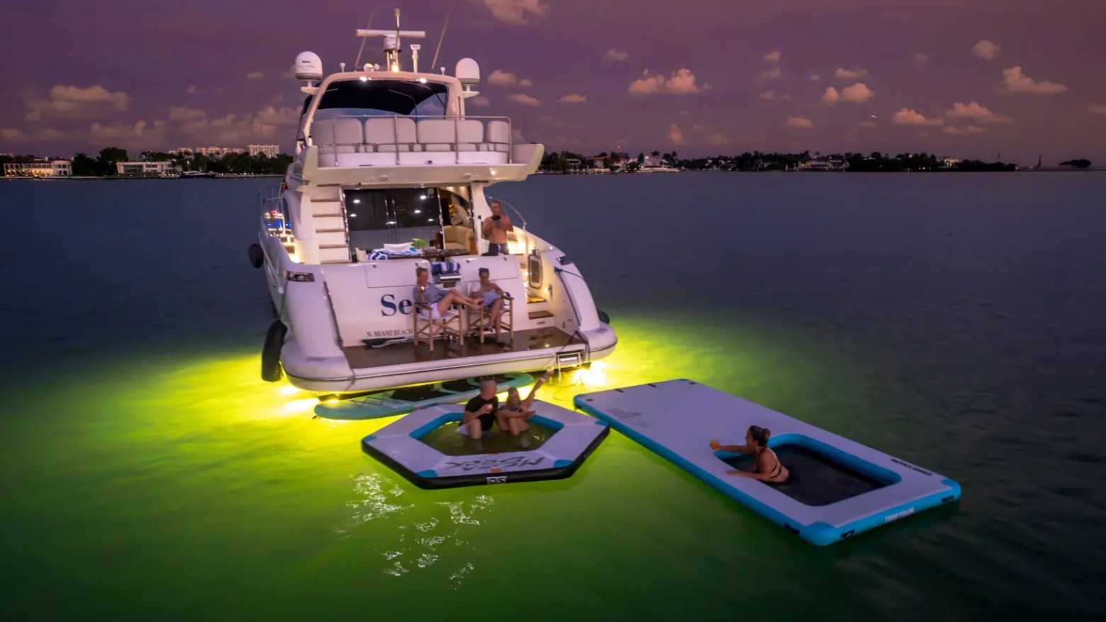 65' Azimut Yacht Charter at night in Miami with underwater lights, Magic Carpet & luxury floating lounge.