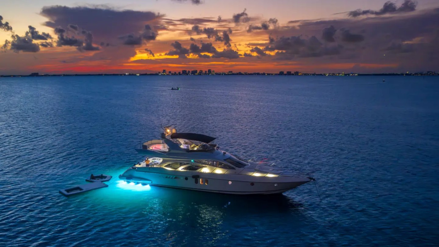 65' Azimut Yacht Charter at sunset on Biscayne Bay with blue underwater lights, Magic Carpet & floating lounge in Miami.