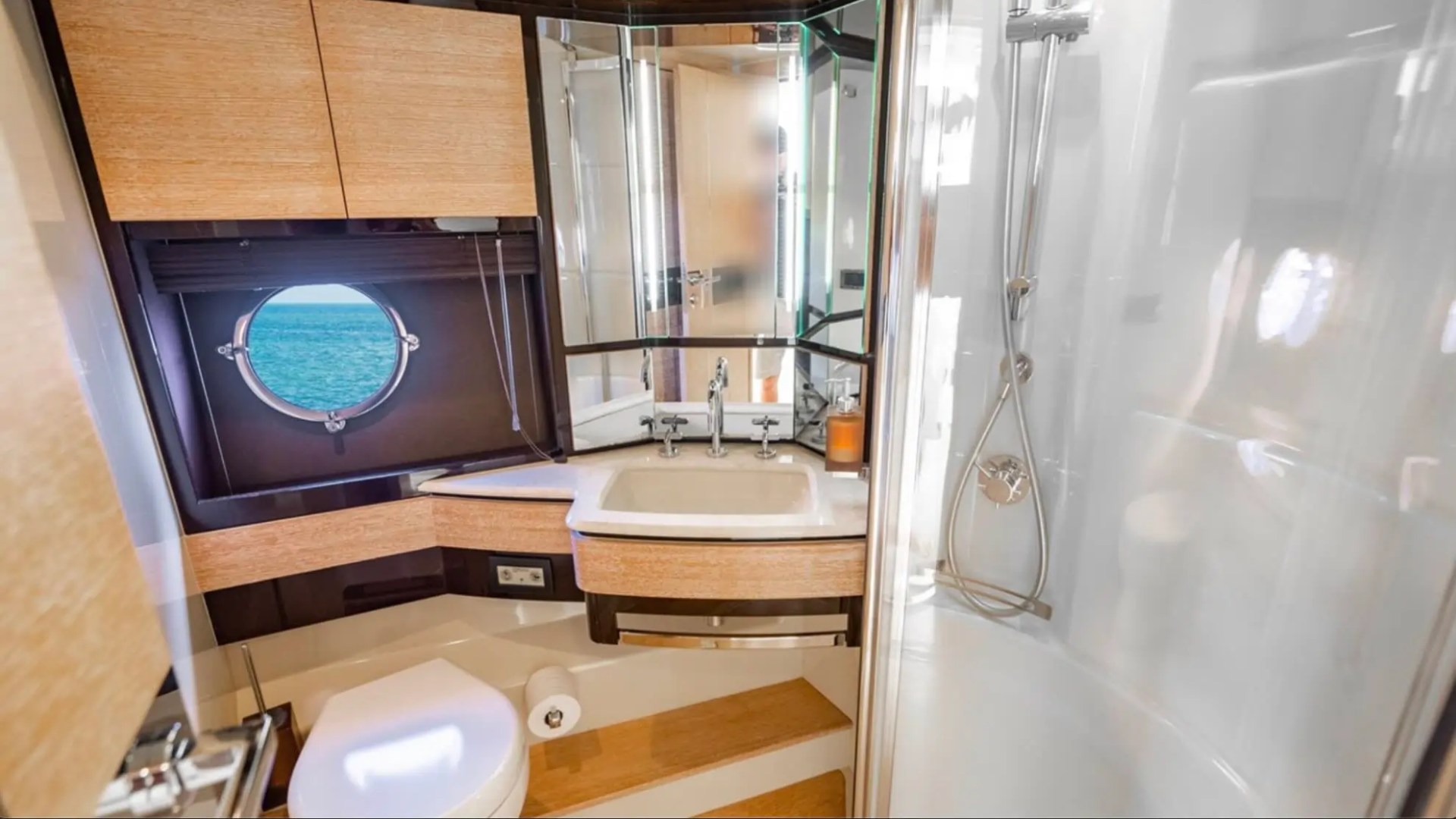70' Azimut Yacht Charter luxury ensuite bathroom with glass shower, vanity and ocean-view porthole in Miami.