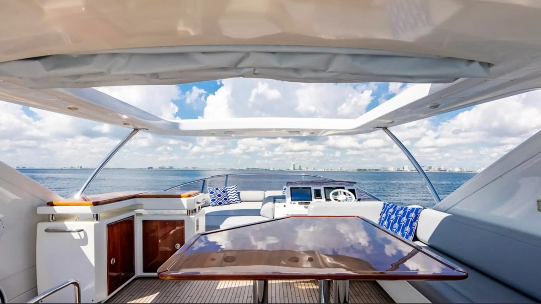 70' Azimut Yacht Charter flybridge dining area with wet bar, helm station and panoramic ocean views in Miami.