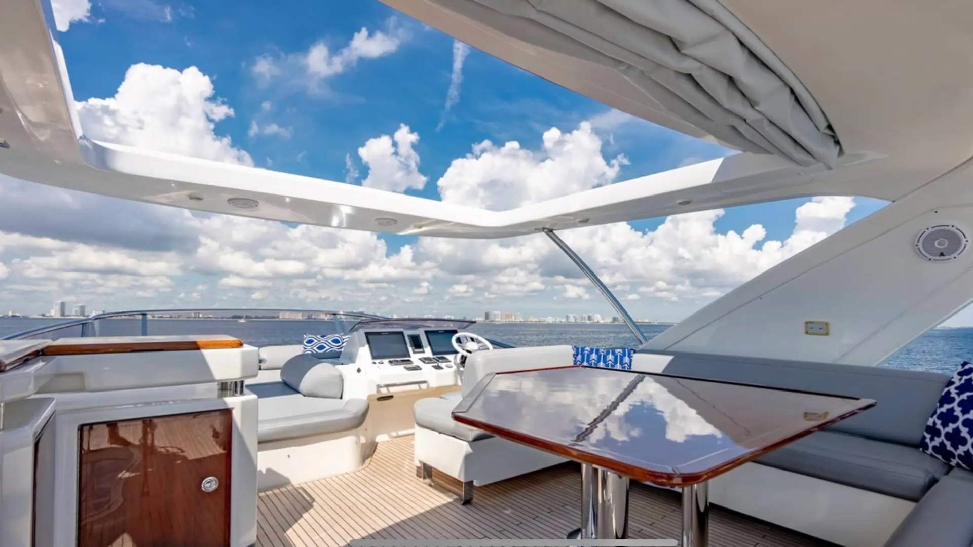 70' Azimut Yacht Charter flybridge with dining table, helm station, lounge seating and panoramic Miami ocean views.