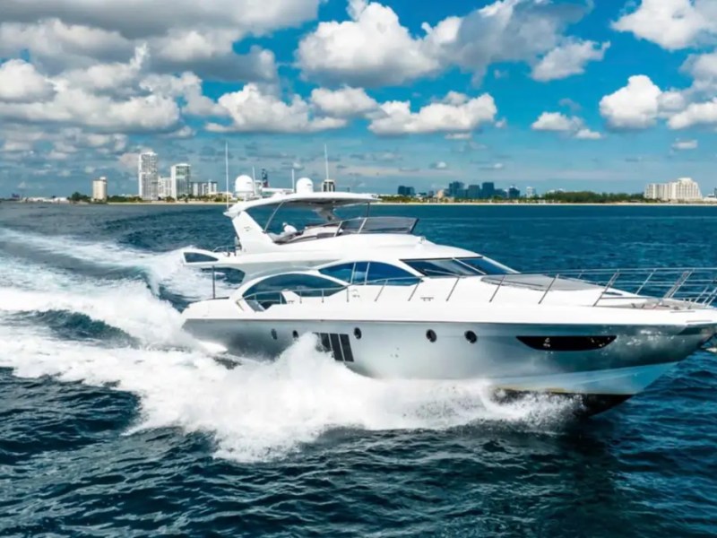 70' Azimut Yacht Charter cruising at high speed across Miami waters with luxury flybridge and sleek Italian design.