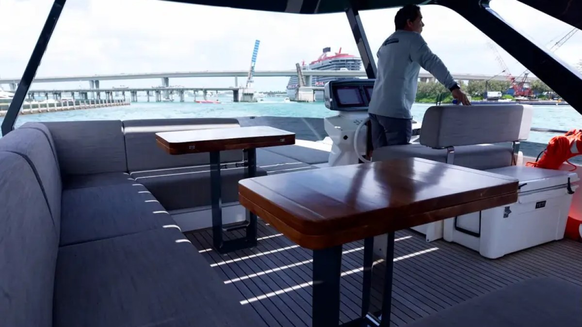 80' Ferretti Yacht Charter flybridge lounge with helm seating and outdoor dining in Miami.