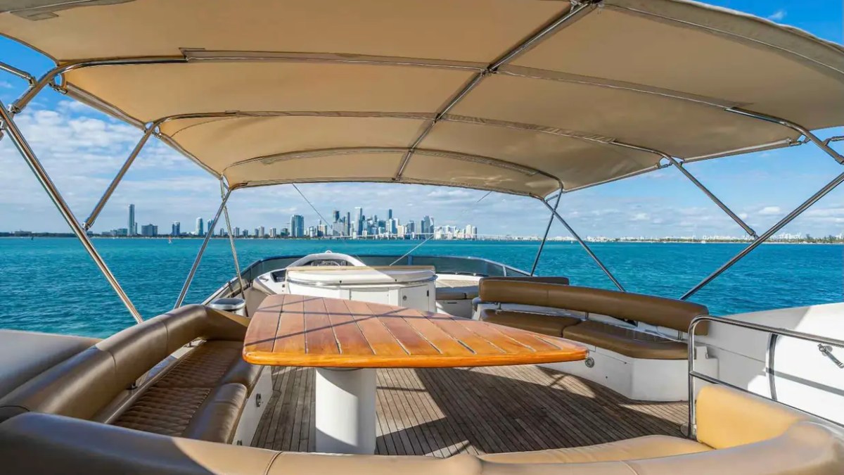90' Azimut Yacht Charter flybridge lounge with shaded dining and panoramic Miami skyline views.