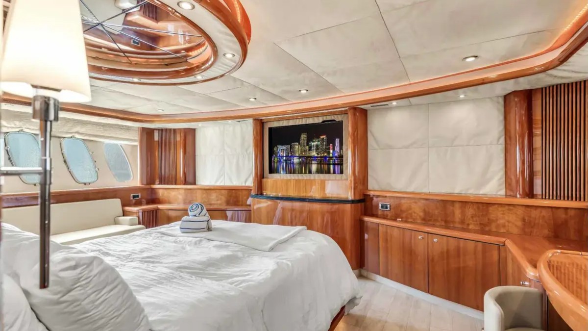 90' Azimut Yacht Charter luxury master stateroom with king bed and elegant wood finishes in Miami.
