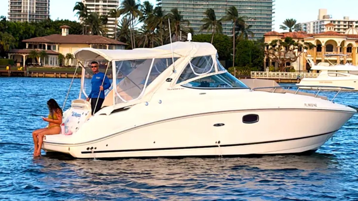 30' SeaRay Boat Rental anchored along the Miami Beach waterfront with luxury high-rise residences in the background, showcasing its sleek express cruiser design on Biscayne Bay.