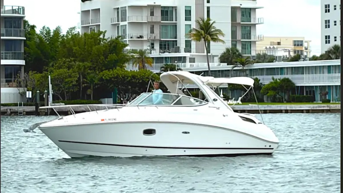 30' SeaRay Boat Rental cruising the Miami Beach waterfront with modern luxury condominiums in the background, showcasing its sleek express cruiser profile on Biscayne Bay.