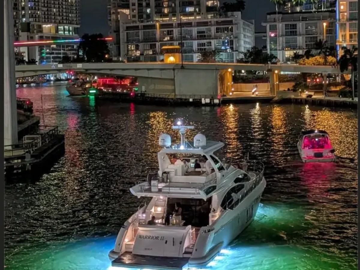 66' Azimut Yacht Charter cruising through Downtown Miami at night with underwater lights.