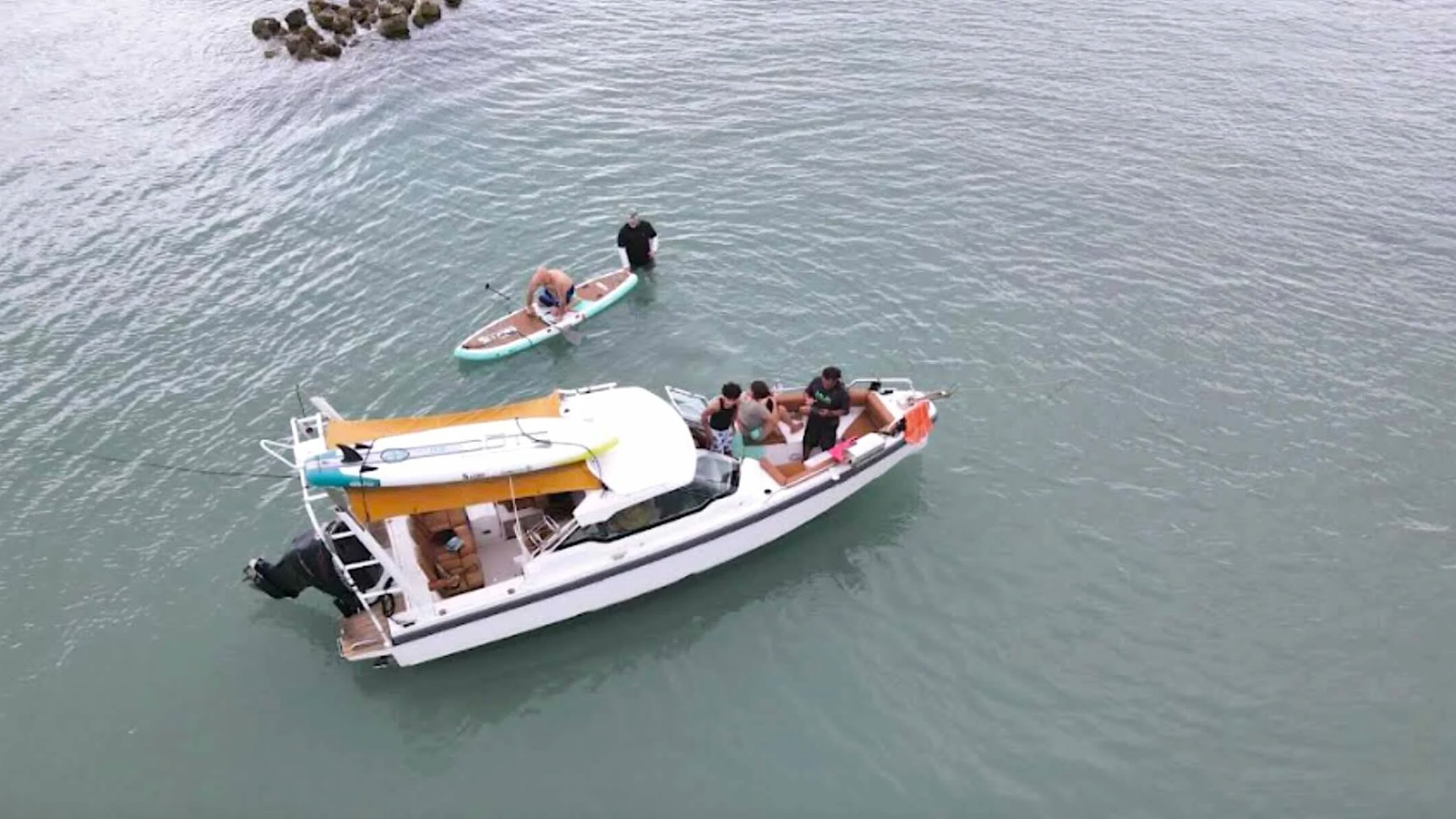 Aerial view of a 26' Axopar Boat Rental anchored with guests paddleboarding near Peanut Island in Riviera Beach.
