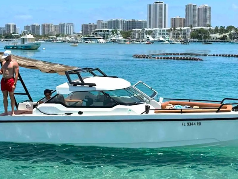 26' Axopar Boat Rental anchored in turquoise water near Peanut Island with the Riviera Beach skyline in the background.