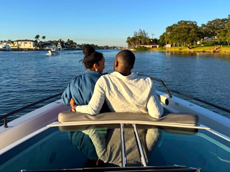 Couple relaxing together on the bow of a 37' Axopar Boat Rental during a Riviera Beach sunset cruise.