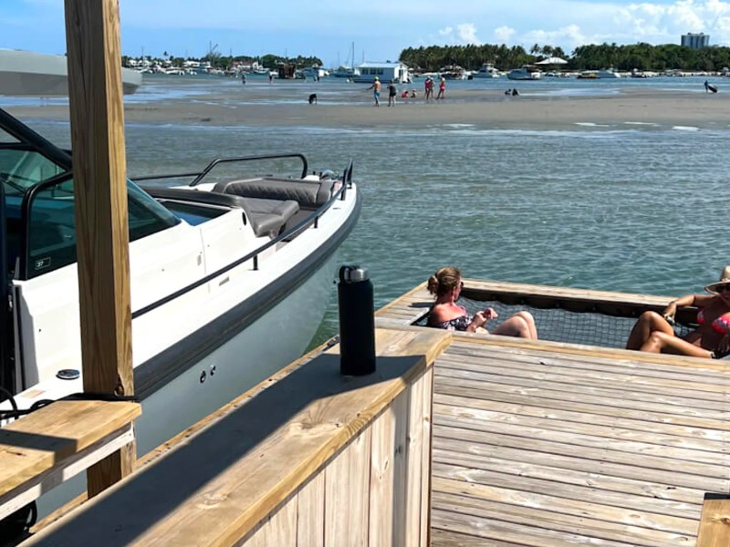 37' Axopar Boat Rental docked beside a floating water lounge near a Riviera Beach sandbar.