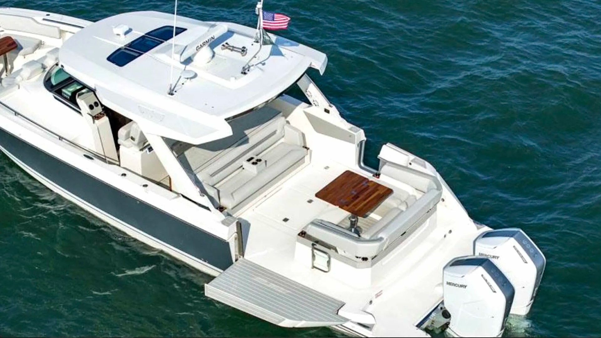 Aft cockpit aboard the 41' Tiara Boat Rental in Riviera Beach with teak table, swim platform, and twin Mercury outboards.