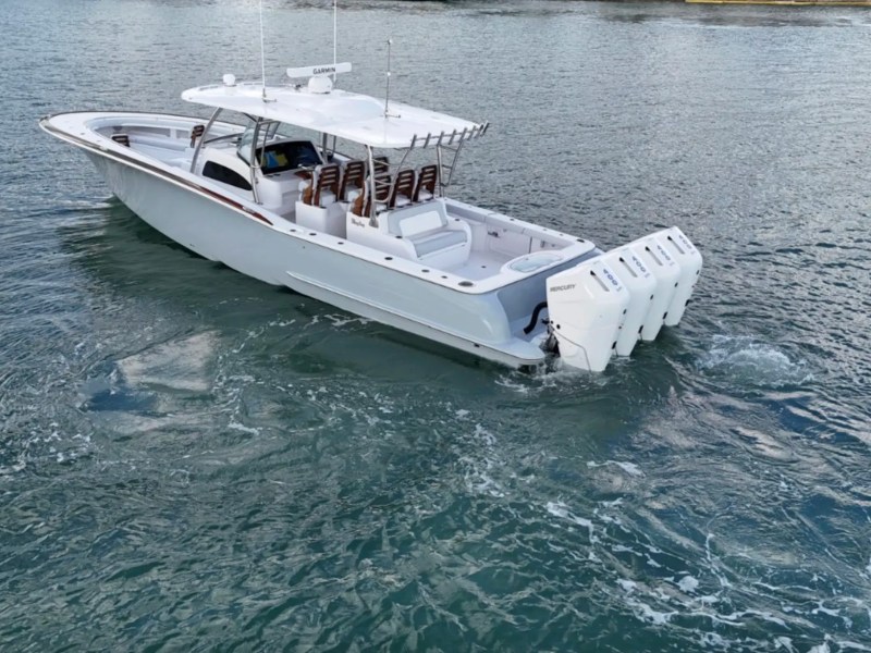 A large white aAerial view of the 43' Mag Bay Boat Rental cruising in Riviera Beach with quad Mercury outboards and spacious luxury layout. with multiple engines on a calm water body.