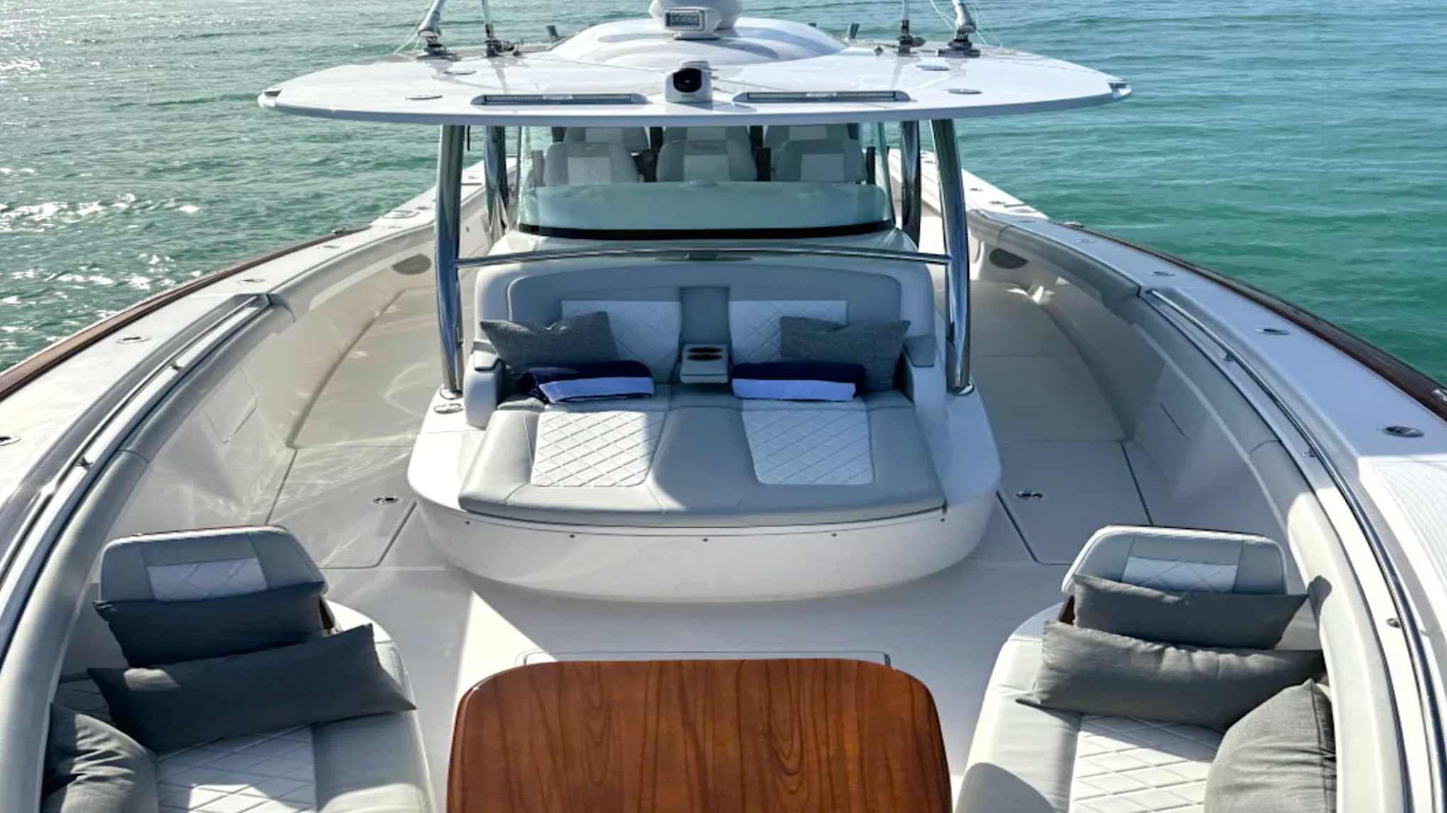 Spacious bow lounge aboard the 43' Mag Bay Boat Rental in Riviera Beach with wraparound seating, teak table, and sun pad.