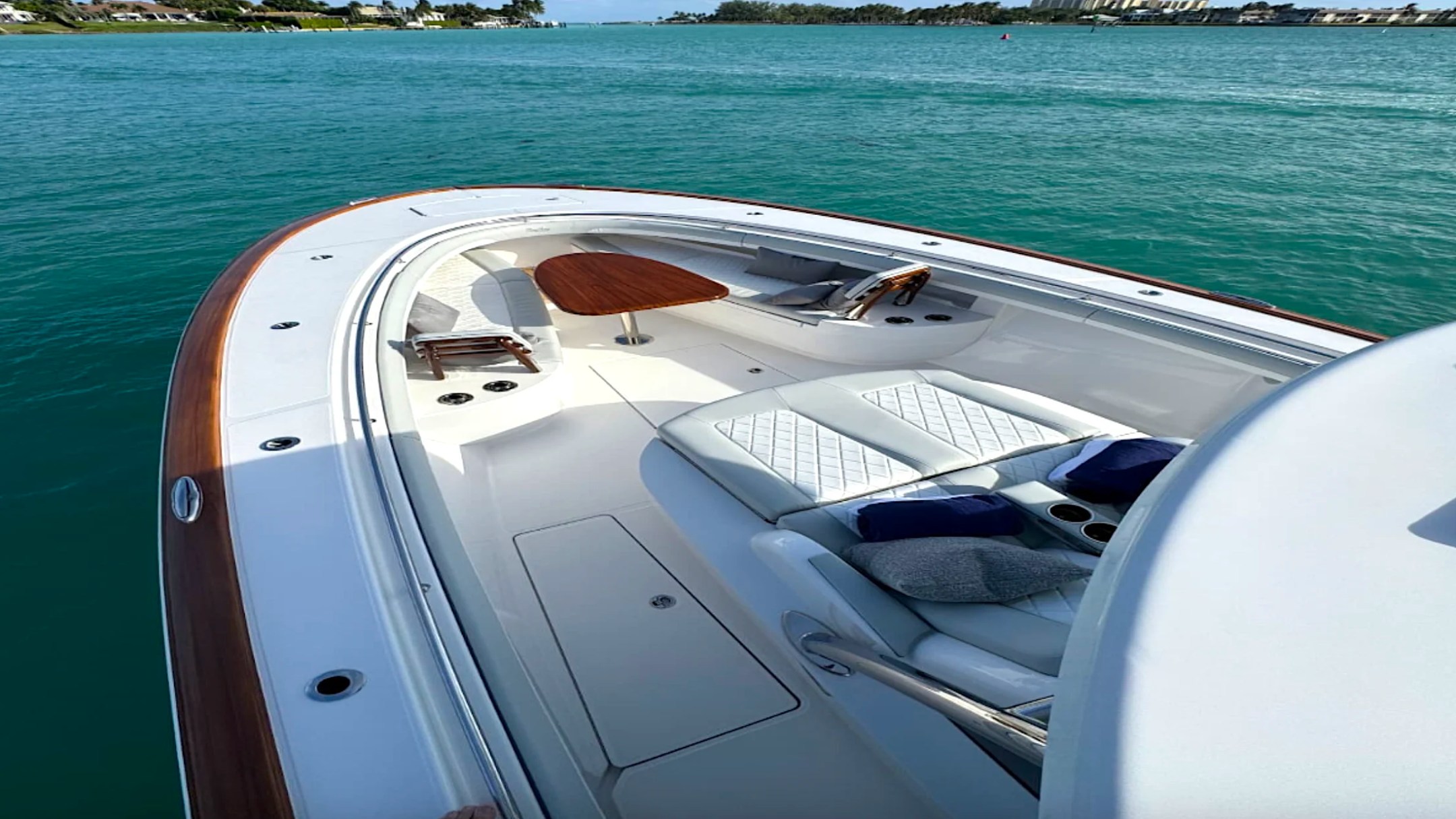 Luxury bow seating aboard the 43' Mag Bay Boat Rental in Riviera Beach with wraparound lounge, teak table, and turquoise Palm Beach waters.