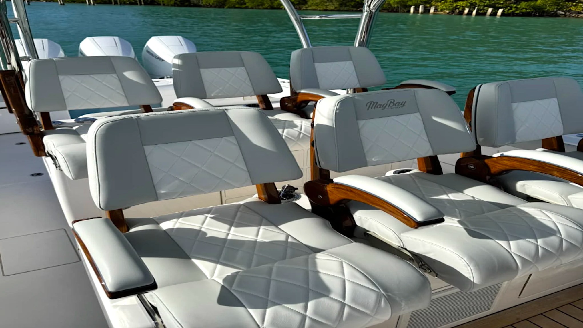 Luxury captain's chairs aboard the 43' Mag Bay Boat Rental in Riviera Beach with premium diamond-stitched upholstery and teak armrests.