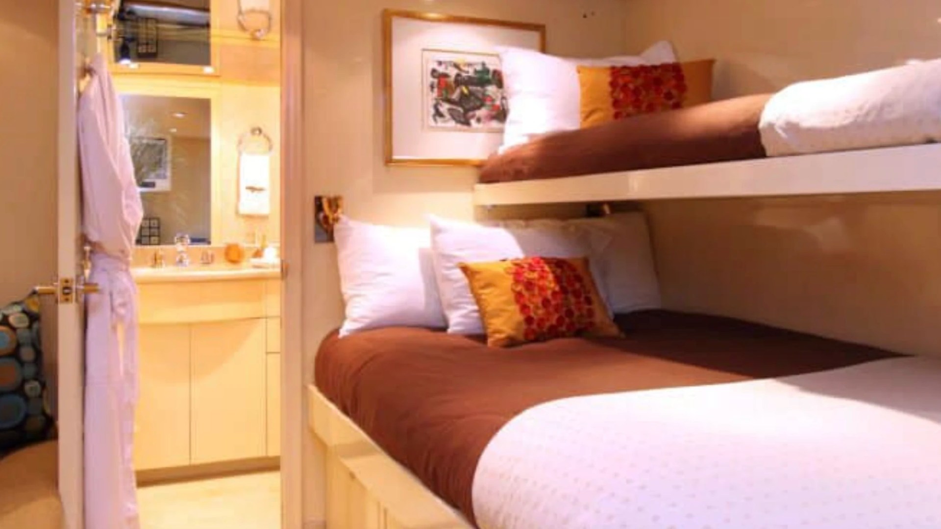 Comfortable guest cabin aboard the 100' Broward Yacht Charter in Fort Myers featuring twin bunk berths, private ensuite access, warm lighting and elegant overnight accommodations.
