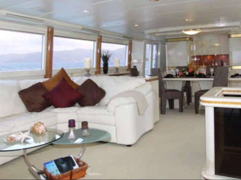Spacious main salon aboard the 100' Broward Yacht Charter in Fort Myers featuring panoramic windows, plush lounge seating, elegant dining area and luxury yacht interior.