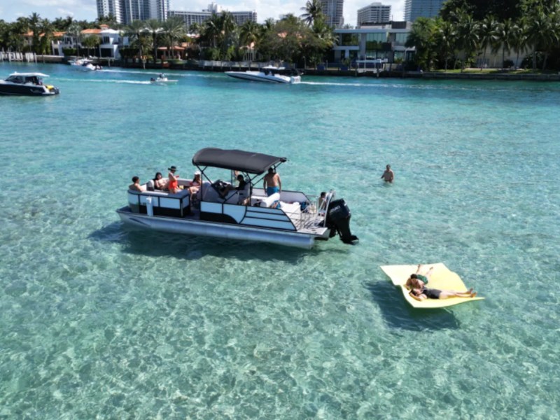 25' Bentley Boat Rental anchored in crystal-clear waters near Hollywood Florida with a Magic Carpet floating mat.