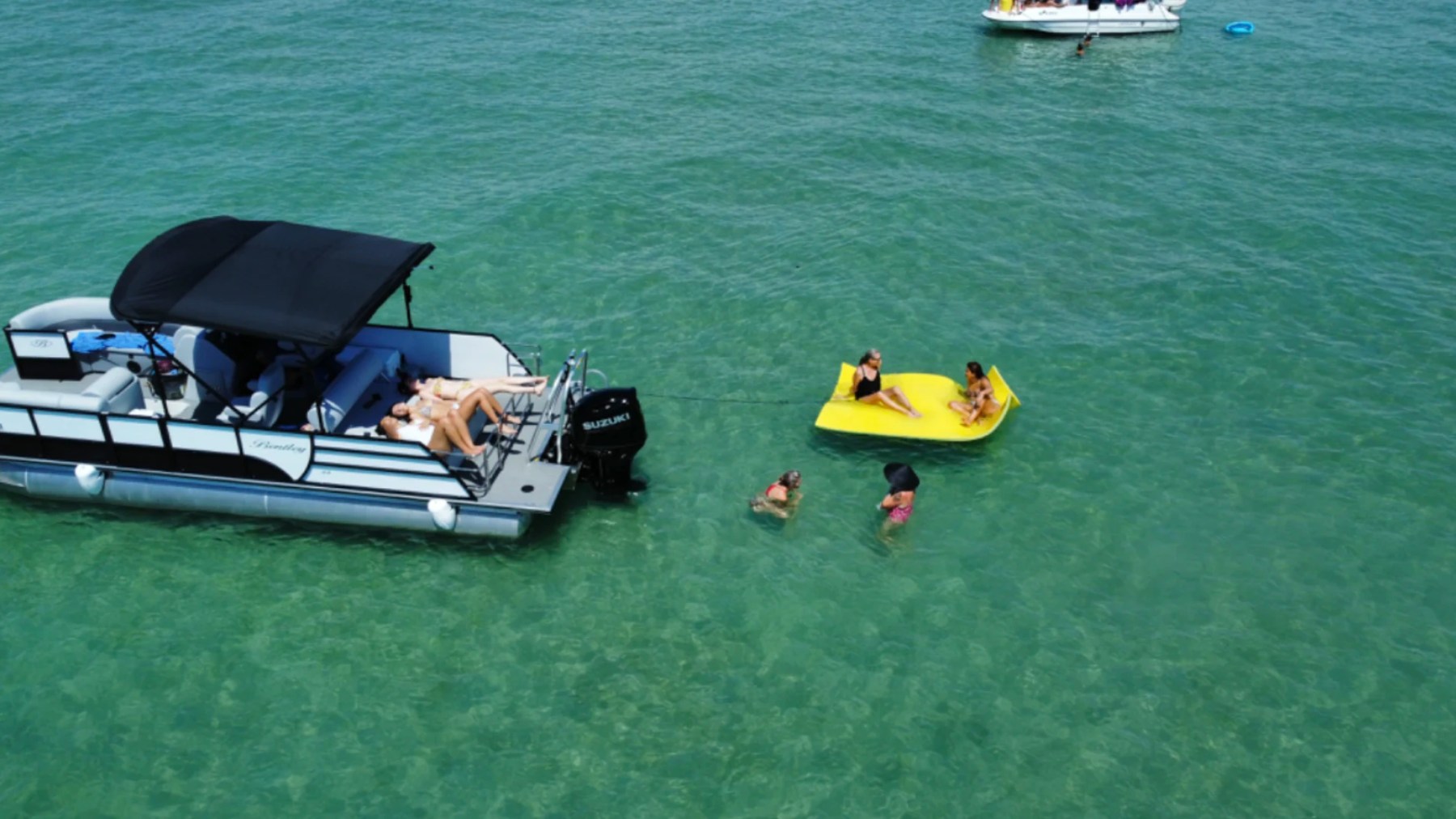 25' Bentley Boat Rental anchored at a Hollywood Florida sandbar with guests swimming and relaxing on a floating mat.