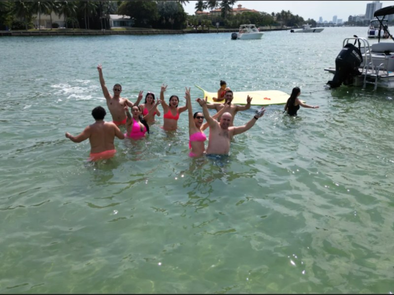 Guests enjoying the shallow waters beside a 25' Bentley Boat Rental at a Hollywood Florida sandbar.