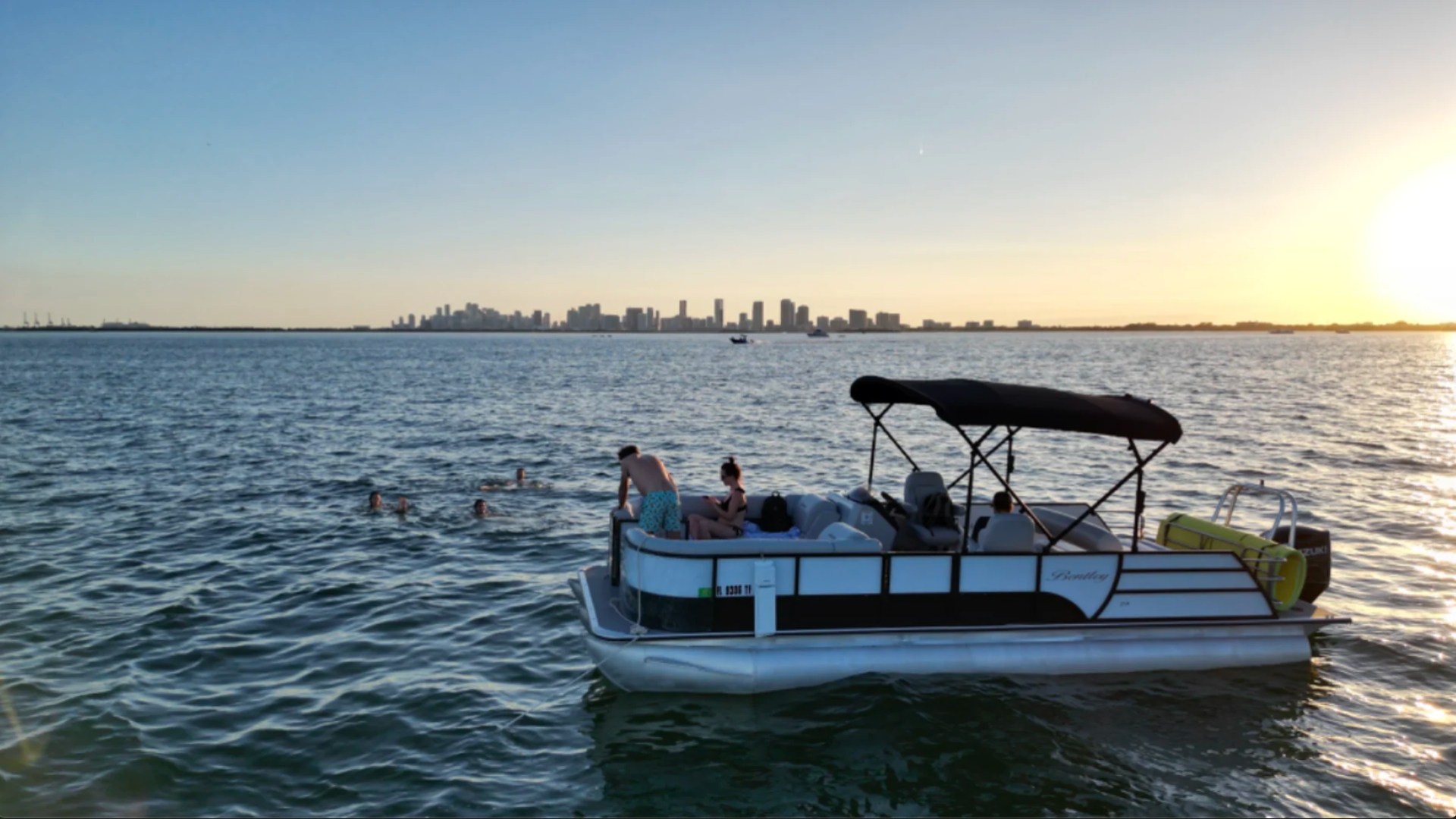 25' Bentley Boat Rental at sunset with guests swimming near the Miami skyline from Hollywood Florida.