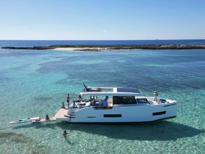 Aerial view of a 50' DeAntonio Yacht Charter anchored in the crystal-clear waters off Palm Beach with guests enjoying the swim platform and surrounding Atlantic Ocean shallows.